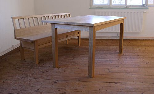 Tisch mit exzentrischer Tischplatte und Sitzbank.